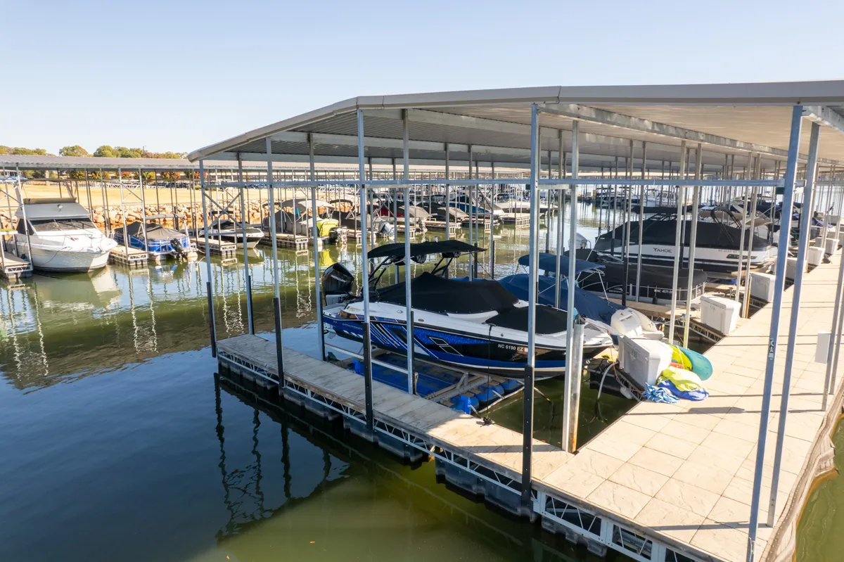 A blue and white speedboat resting on a floating boat lift inside a large covered marina.