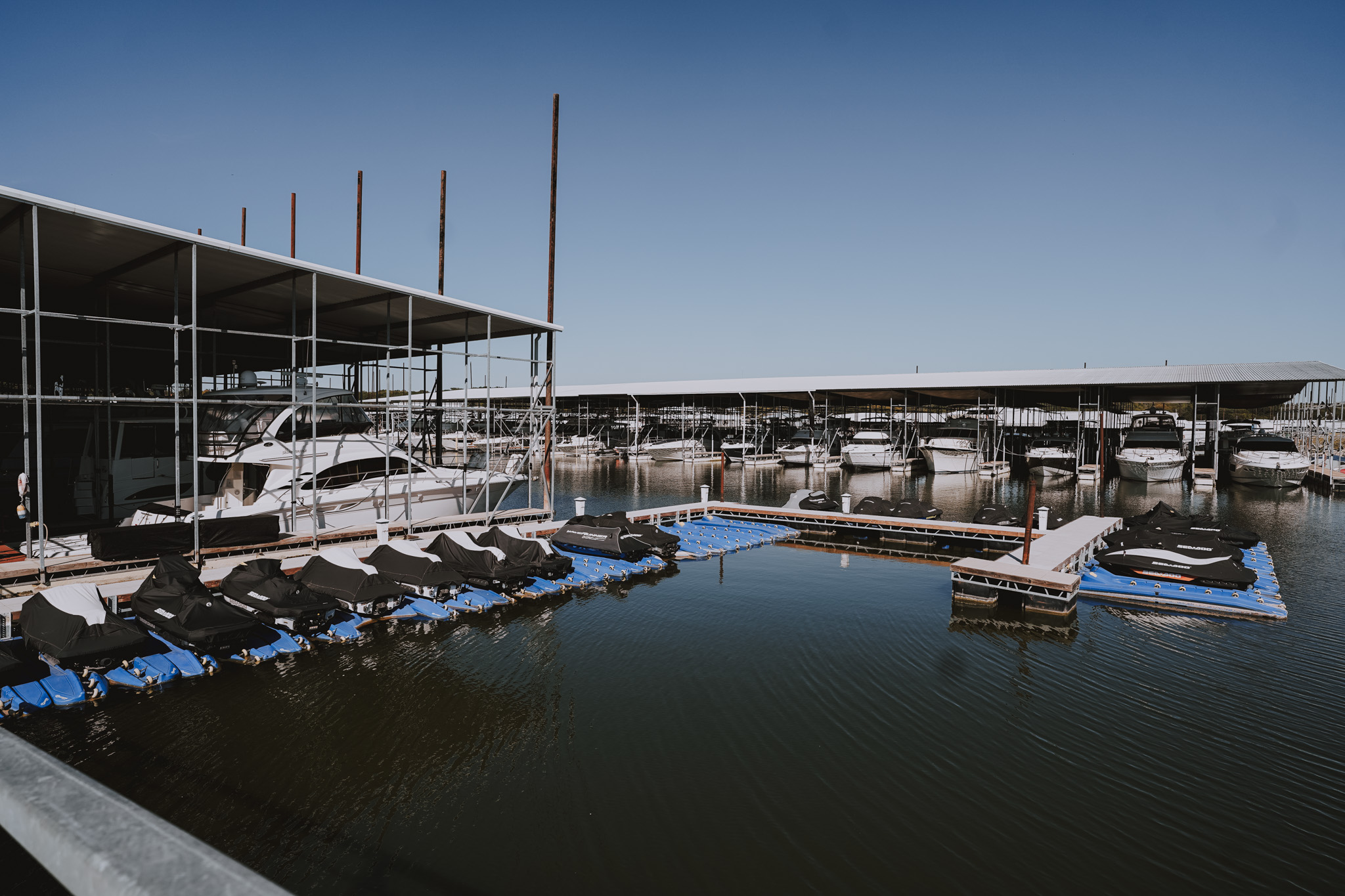 Boat marina with covered yachts docked in water under metal shed