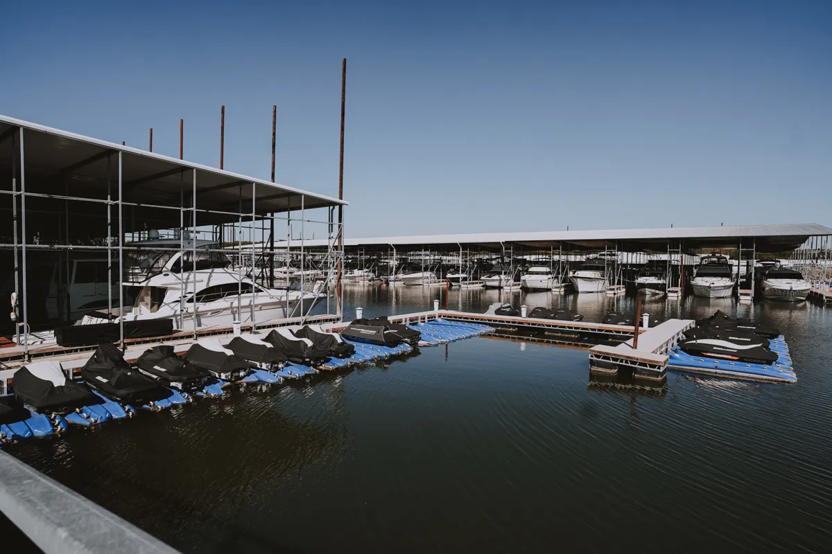 Boat marina with covered yachts docked in water under metal shed
