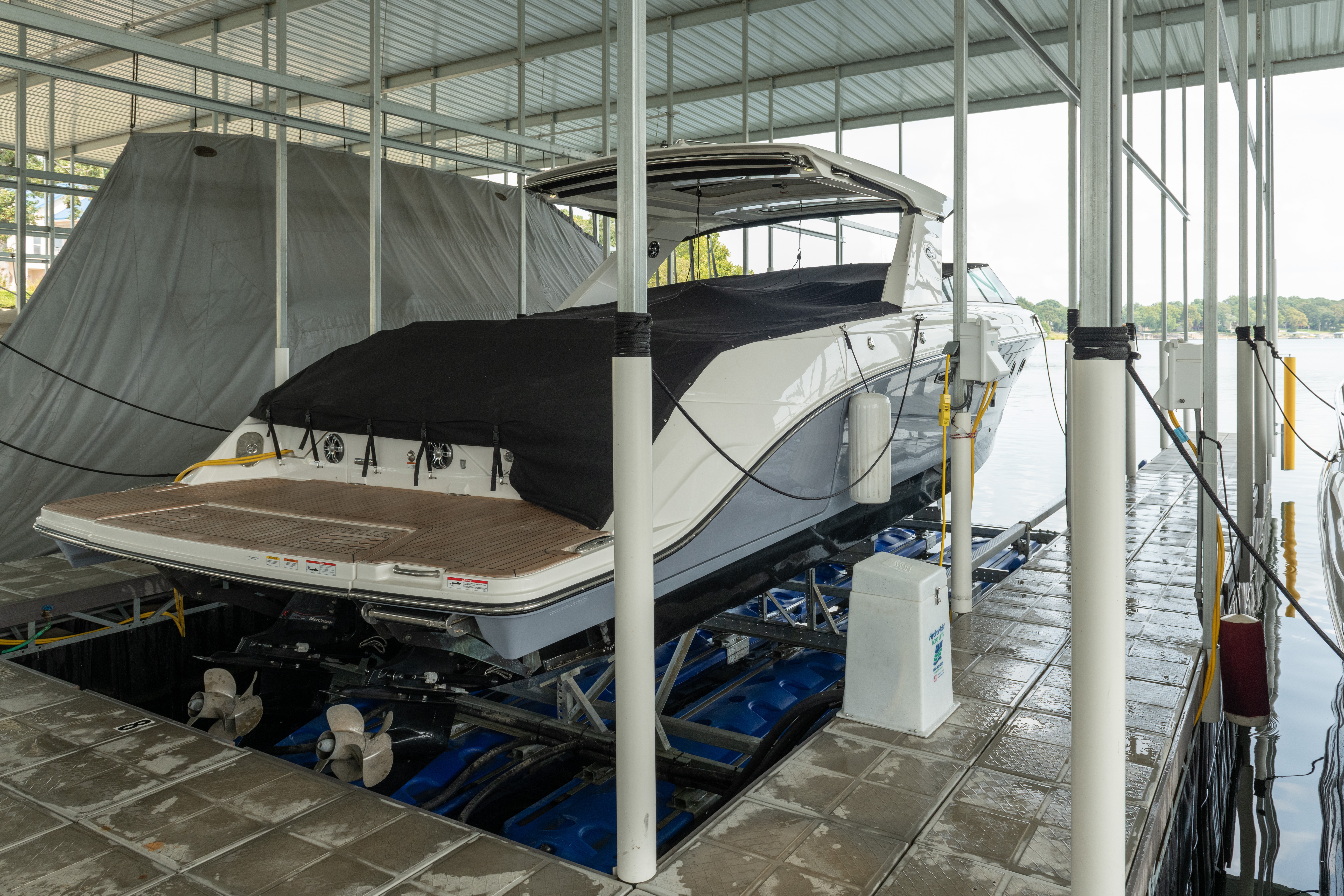 Boat on a lift at a covered marina dock with waterfront view